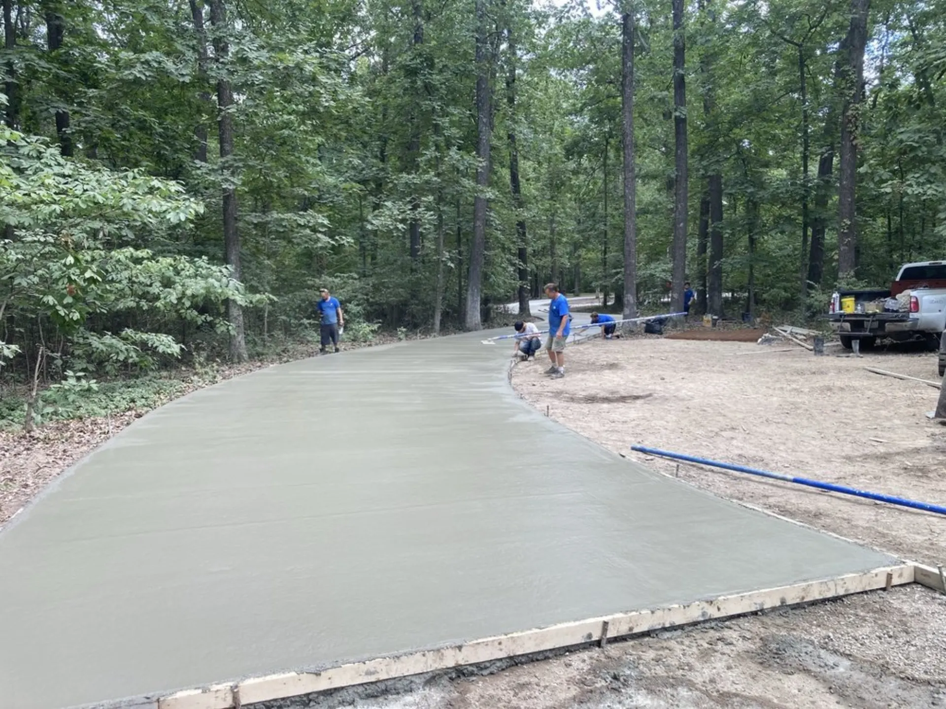 Majestic Concrete crew screeding a fresh concrete pour on a wooded residential lot in Edwardsville