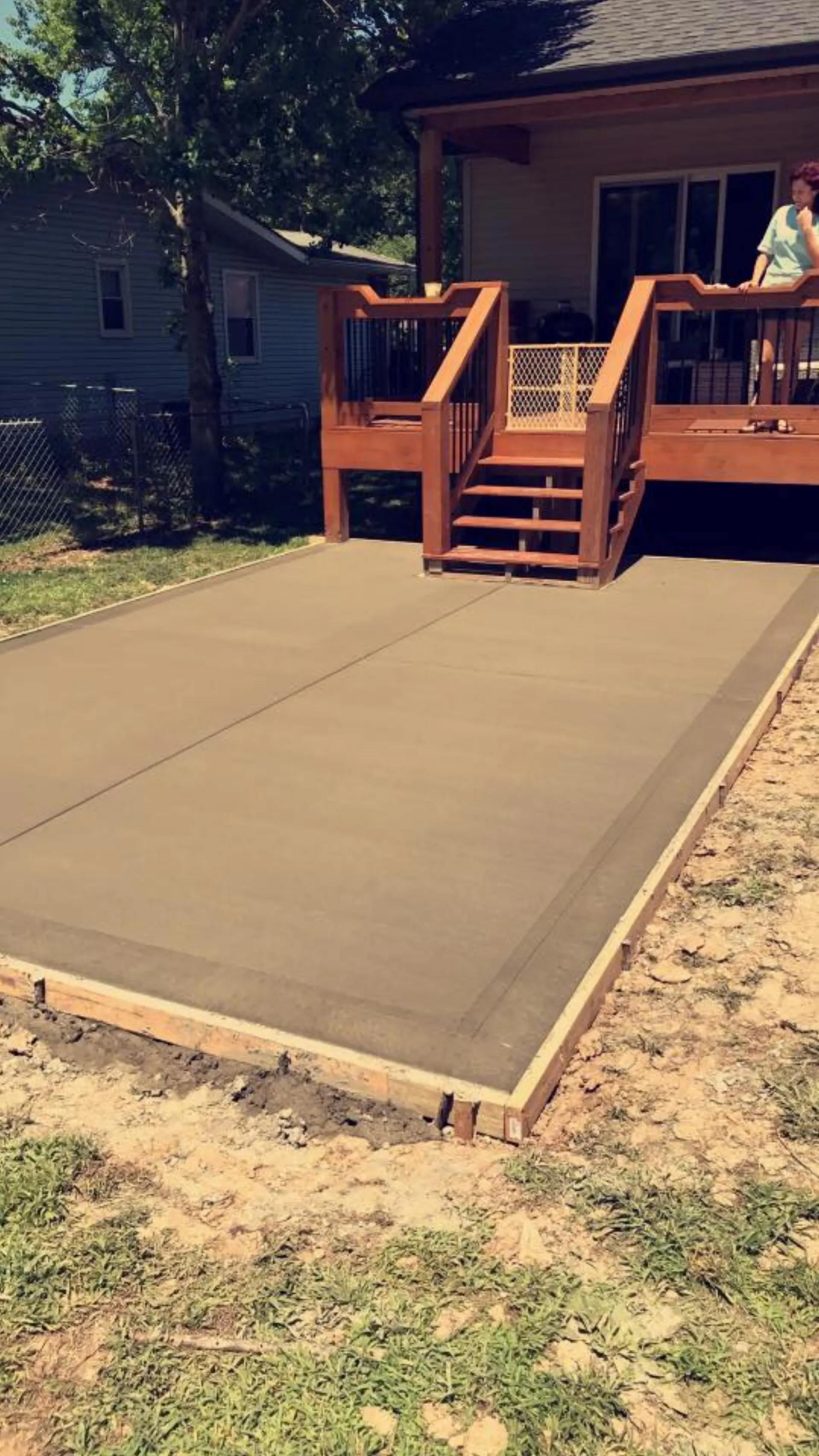 Concrete patio off a wood deck in a residential backyard