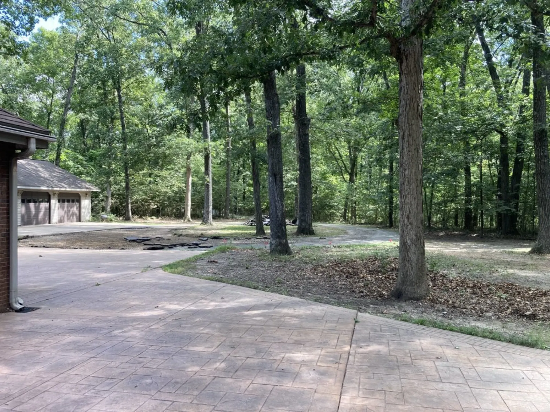 Wide stamped concrete driveway curving around a residential home with wooded surroundings