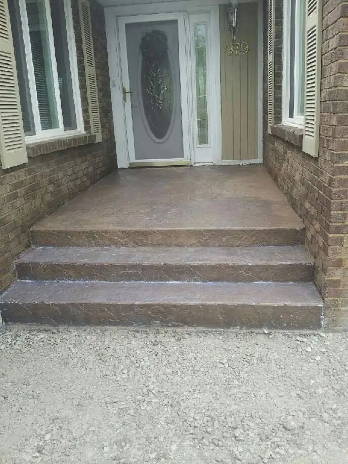 Stamped concrete walkway curving from a brick home toward the front yard